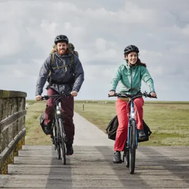 Nachhaltig reisen durch die Wahl des richtigen Verkehrsmittels: Das Bild zeigt ein Paar, das im Urlaub Fahrrad fährt.