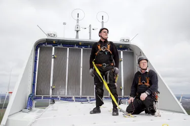 Das Bild zeigt Henry Löwenherz und Marko Bartsch, die mit Kletterausrüstung auf einem Windrad stehen und dieses auf Schäden begutachten.