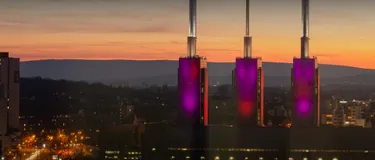Dieses Bild zeigt eine Luftaufnahme von Hannover-Linden. Im Vordergrund ist das enercity-Heizkraftwerk zu sehen, welches farbenprächtig in der Abenddämmerung leuchtet.