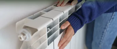 Junge Frau wärmt ihre Hände an der Heizung