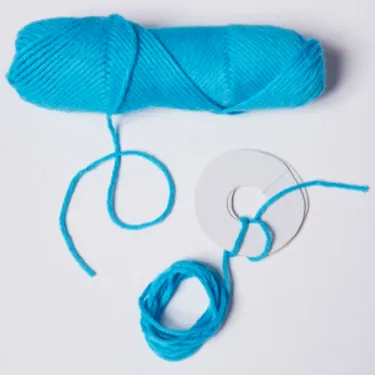 Schritt 2: Das Bild zeigt, wie Wollreste an die ausgeschnittenen Scheiben gewickelt werden.