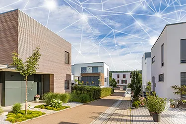 Über das Foto einer modernen Wohnanlage wurde das Rendering eines engmaschigen Netzes gelegt, das das smarte Stromnetz darstellt.