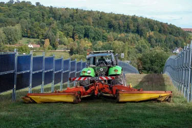 Landwirtschaftliche Maschine fährt zwischen bifazialen Solarmodulen hindurch