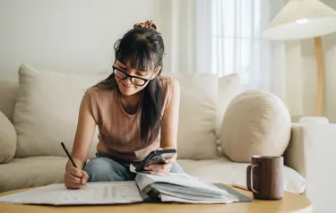 Eine Frau sitzt auf einem Sofa und berechnet die Kosten für eine Innendämmung