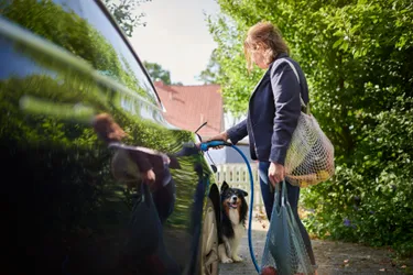 Eine Frau lädt ein Elektroauto an einer privaten Ladestation