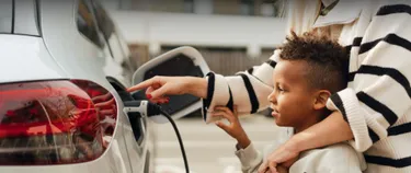 Junge und Frau laden ein E-Auto.