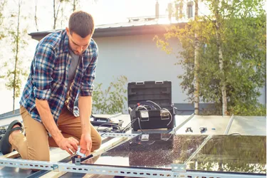 Ein Mann installiert eine PV-Anlage auf einem Carportdach