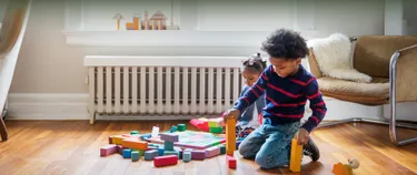 Kinder spielen mit Bauklötzen vor Heizung