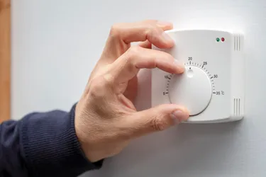 Ein Thermostat für den Wohnraum wird per Hand auf 20 Grad Celsius eingestellt