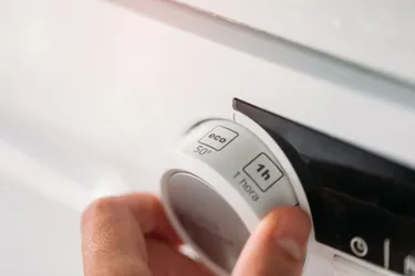Nahaufnahme einer Hand, die an einer Waschmaschine das Eco-Programm einstellt