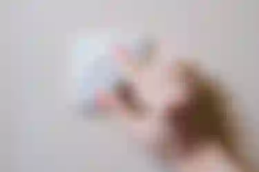 Nahaufnahme einer Frauenhand die an einem an einer Zimmerwand installierten Dimmer dreht