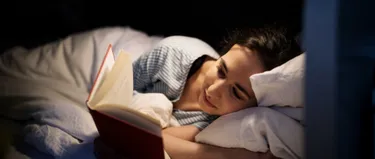 Frau liegt im Bett und liest