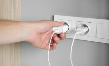 Nahaufnahme einer Doppelsteckdose in der zwei Smartphone-Ladekabel stecken