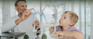 Ein Vater und sein Sohn spielen mit Miniatur-Windkraftanlagen.