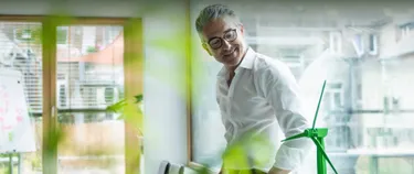 Ein Mann schaut lächelnd auf ein Modell einer Windkraftanlage.