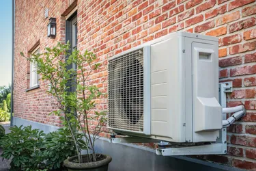 Eine Wärmepumpe ist an einer Hauswand befestigt.