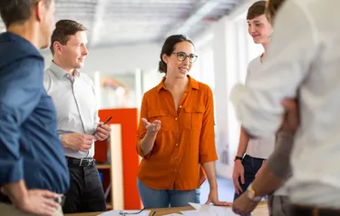 Nahaufnahme von fünf Menschen die sich in einem Büro miteinander besprechen
