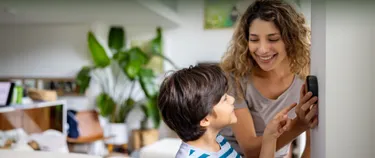 Mutter und Sohn zu Hause stellen die Temperatur mit einem intelligenten Thermostat ein.