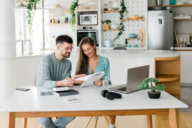 Eine Frau und ein Mann sitzen an einem Esstisch vor einem Laptop