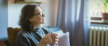 Eine Frau sitzt auf dem Sofa vor einer Heizung