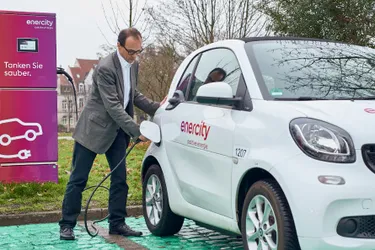 Ein Mann tankt sein E-Auto an einer Ladesäule auf.
