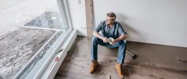 Ein Mann genießt sitzend eine Pause in einem unfertigen Neubau.