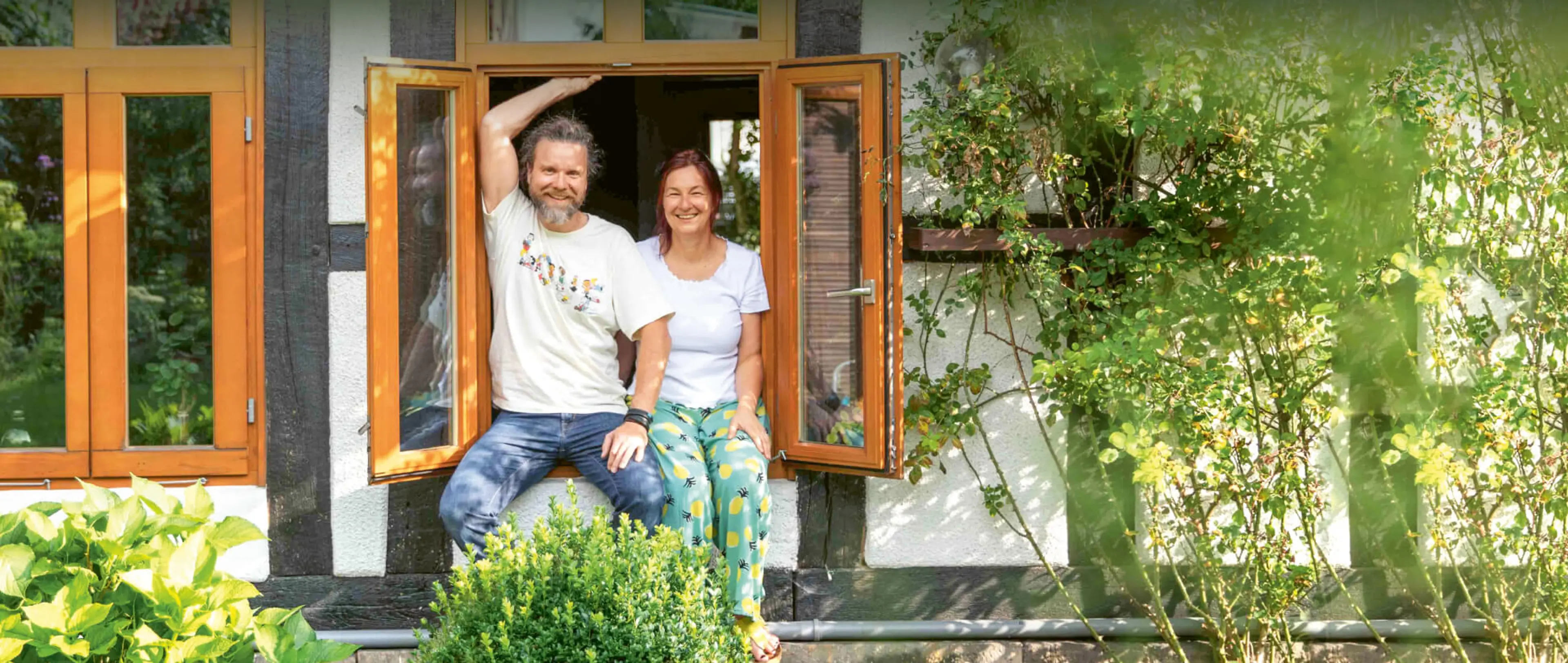 Klimafreundliche Wärme für den Altbau Petra und Mathias von Elling sitzen auf der Fensterbank ihres Hauses und schauen in ihren Garten.