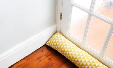 Nahaufnahme eines auf dem Boden vor einer Tür liegenden selbst genähten Zugluftstoppers