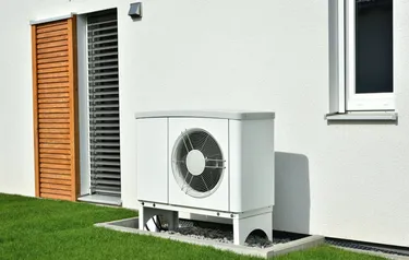 Großaufnahme einer vor einer Hausfassade installierten Wärmepumpe