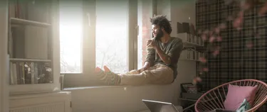 Ein Mann sitzt an seinem Fenster und schaut hinaus.