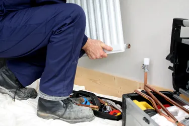 Ein Monteur installiert einen neuen Heizkörper in einem Wohnraum 