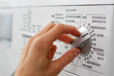 Nahaufnahme einer Hand die an einer Waschmaschine die Programmwahl auf Eco einstellt