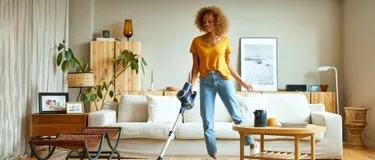 Eine Frau mit dem Staubsauger im Wohnzimmer
