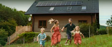 Familie vor einem Einfamilienhaus mit Solar.