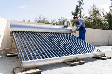 Ein Handwerker installiert auf einem Hausdach eine Solarthermie-Anlage