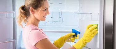 Eine Frau taut den Kühlschrank ab