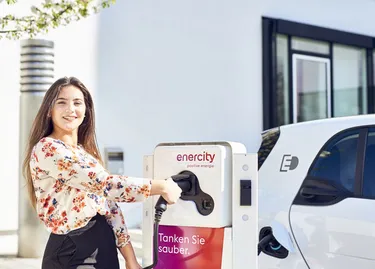 Eine Frau lädt ihr E-Auto an einer Ladestation auf ihrem Stellplatz.