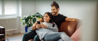 Ein Mann und eine Frau liegen auf dem Sofa unter einer Decke.