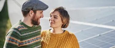 Ein Paar steht vor einer Photovoltaik-Anlage und schaut sich an.