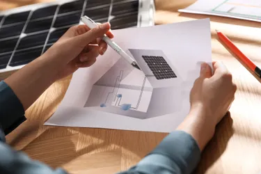 Nahaufnahme eines Bauplans, der ein Haus mit einer Photovoltaikanlage auf dem Dach und einem Batteriespeicher im Keller zeigt.