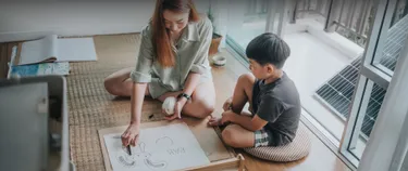 Eine Mutter und ihr Sohn spielen im Wohnzimmer. Auf dem Balkon sieht man ein Balkonkraftwerk.