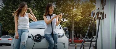 7 Mythen über E-Autos: Das Bild zeigt zwei junge Frauen an einer E-Ladesäule, die einen Selfie machen