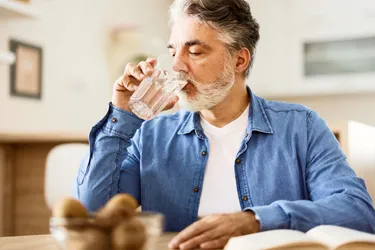 Ein Mann trinkt Wasser aus einem Glas.