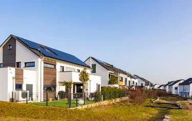 Eine Wohnsiedlung mit Häusern, auf deren Dächern PV-Anlagen installiert sind.