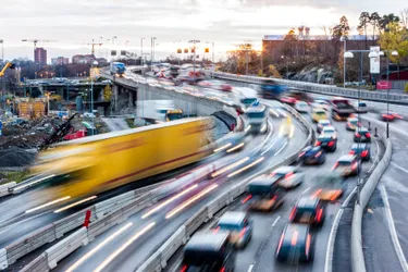 Kurviger Stadtautobahnabschnitt, auf dem zahlreiche Autos und Lkw fahren.