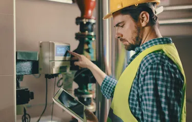 Nahaufnahme eines Heizungsinstallateurs der eine Heizung auf ihre Effizienz hin überprüft