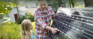 Mann zeigt Mädchen eine Photovoltaikplatte