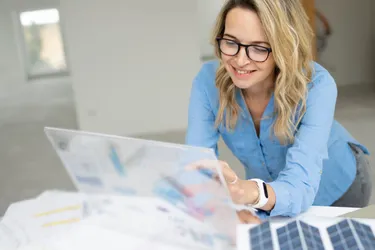 Eine Frau sitzt am Schreibtisch und schaut auf einen Bildschirm.