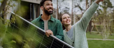 Ein Paar steht im Garten und hält ein Solarmodul in den Händen.