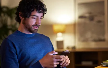 Junger Mann steuert seine smarte Heizung per Handy App